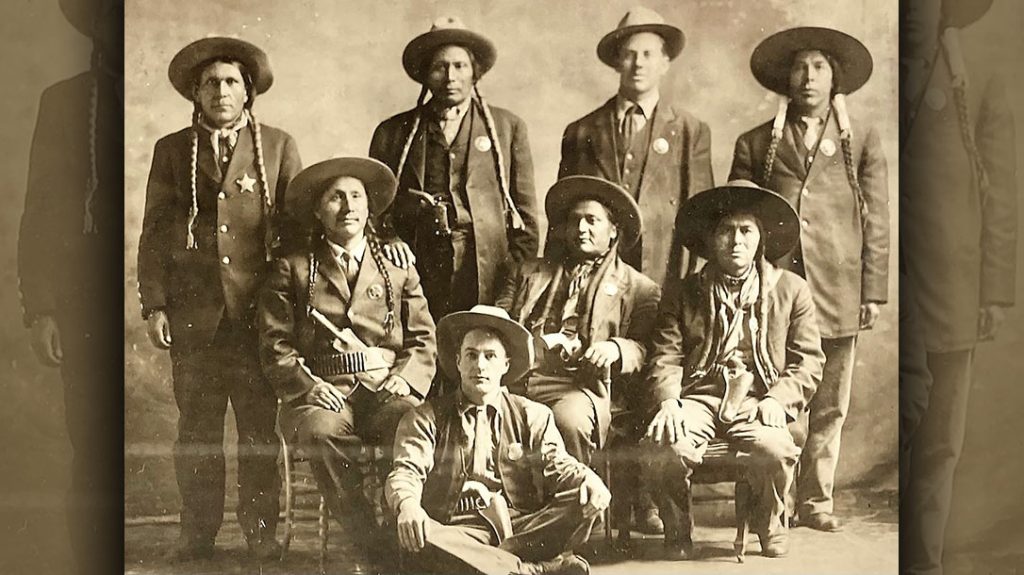 Here Fred Lambert is seen sitting in front of several members of the Indian Police force, with his six-gun prominently displayed.